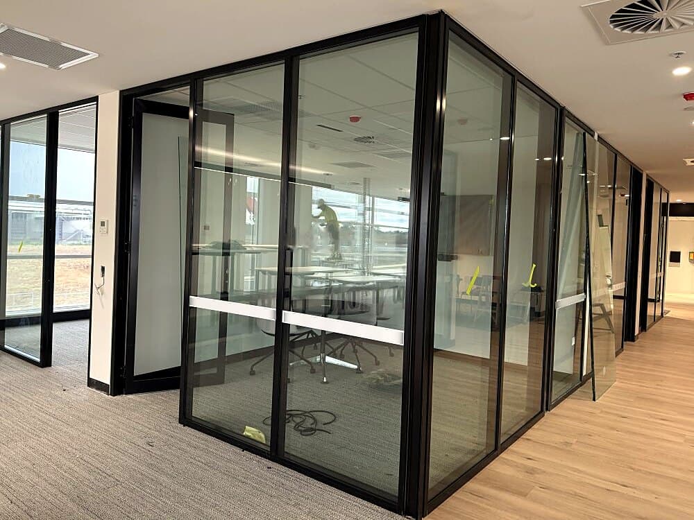 Black-framed acoustic glass partitions and doors in an office fit-out